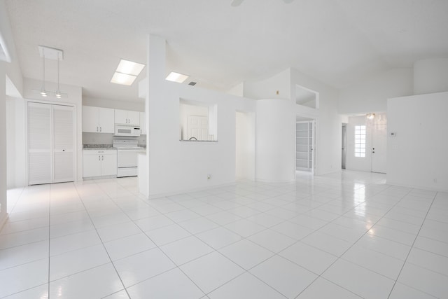 unfurnished living room with high vaulted ceiling and light tile patterned floors