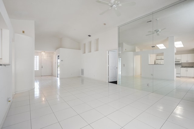 spare room featuring ceiling fan, high vaulted ceiling, light tile patterned flooring, and baseboards