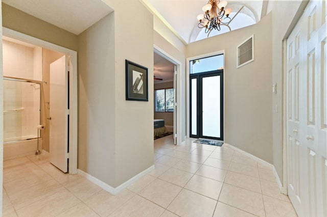 entrance foyer featuring light tile patterned floors, baseboards, visible vents, and an inviting chandelier