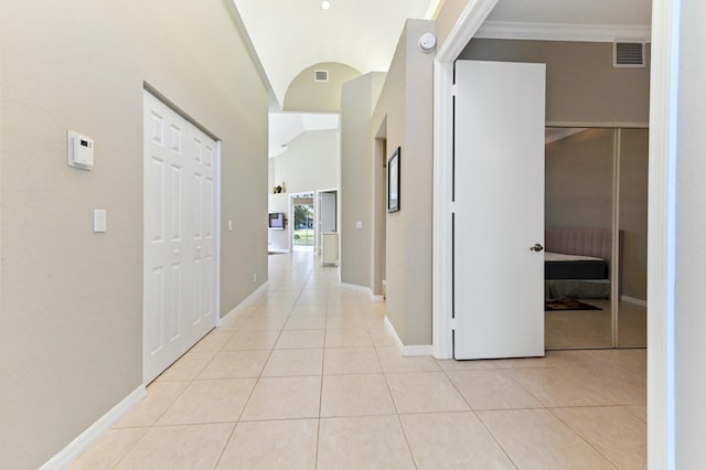 corridor with light tile patterned floors, vaulted ceiling, visible vents, and baseboards