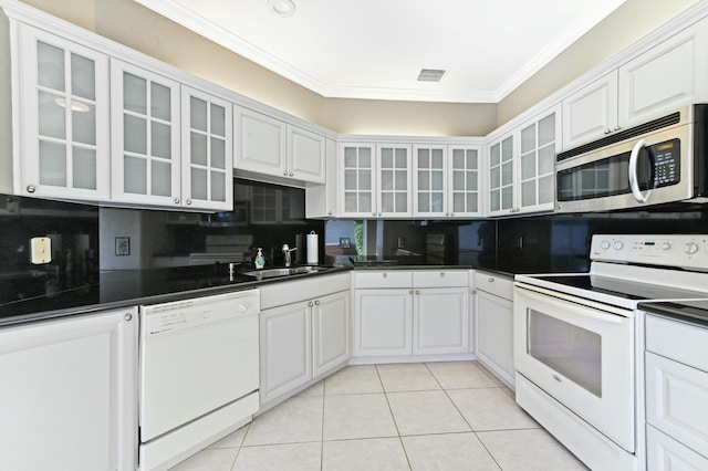 kitchen featuring white appliances, dark countertops, a sink, and white cabinetry