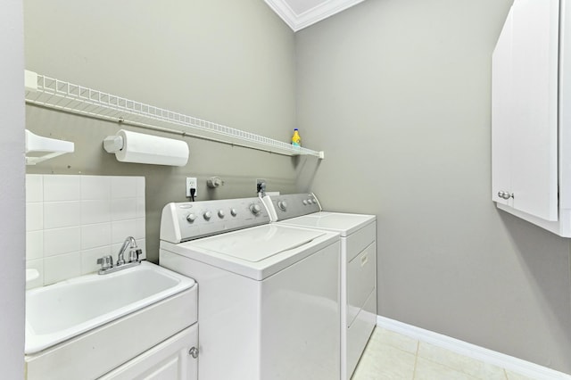 laundry room featuring washing machine and clothes dryer, cabinet space, light tile patterned flooring, a sink, and baseboards