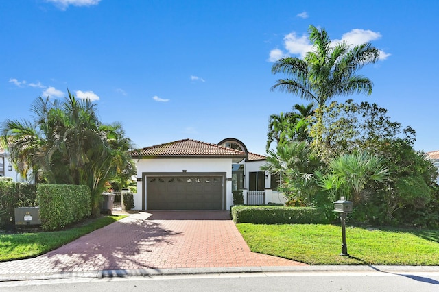 mediterranean / spanish-style house featuring an attached garage, a tiled roof, decorative driveway, stucco siding, and a front yard