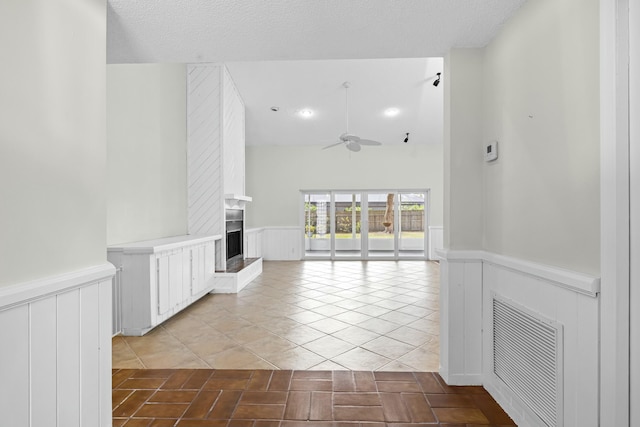 interior space featuring a large fireplace, visible vents, and wainscoting