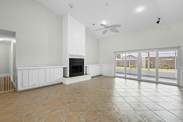 unfurnished living room with light tile patterned floors, high vaulted ceiling, a high end fireplace, and a ceiling fan