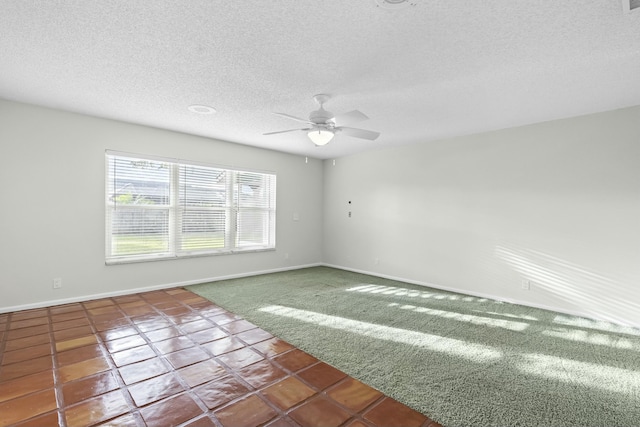 carpeted empty room featuring tile patterned flooring, ceiling fan, baseboards, and a textured ceiling