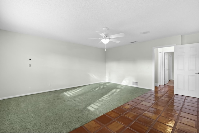 carpeted empty room with a textured ceiling, ceiling fan, visible vents, and baseboards