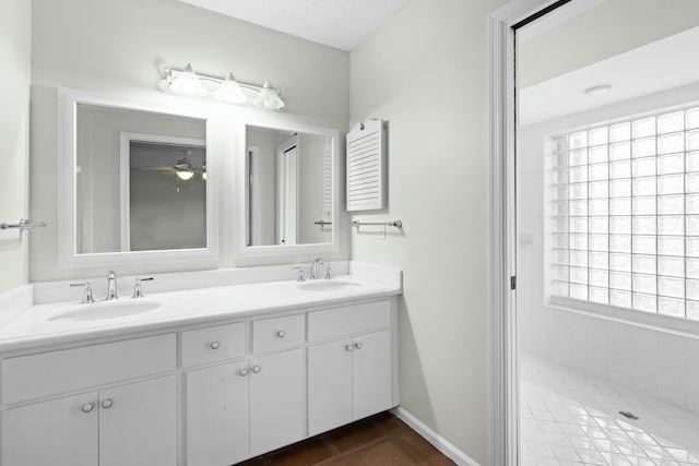 bathroom featuring a sink, a textured ceiling, baseboards, and double vanity