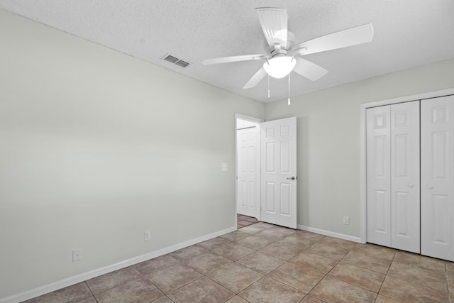 unfurnished bedroom with a textured ceiling, light tile patterned floors, a closet, and visible vents