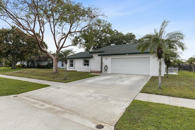 ranch-style home with concrete driveway, an attached garage, fence, a front lawn, and stucco siding