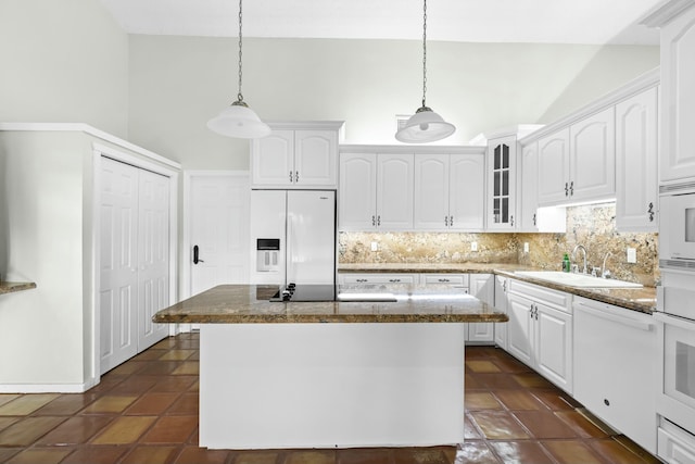 kitchen featuring white appliances, a sink, white cabinetry, backsplash, and glass insert cabinets