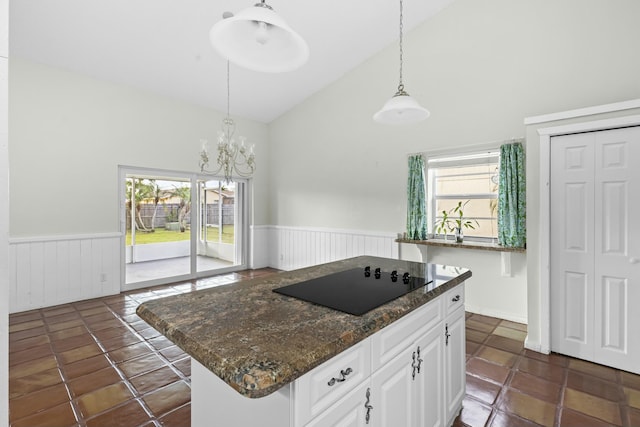 kitchen featuring pendant lighting, black electric stovetop, white cabinets, and wainscoting