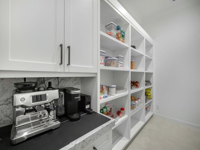 interior space featuring tasteful backsplash, white cabinets, and baseboards