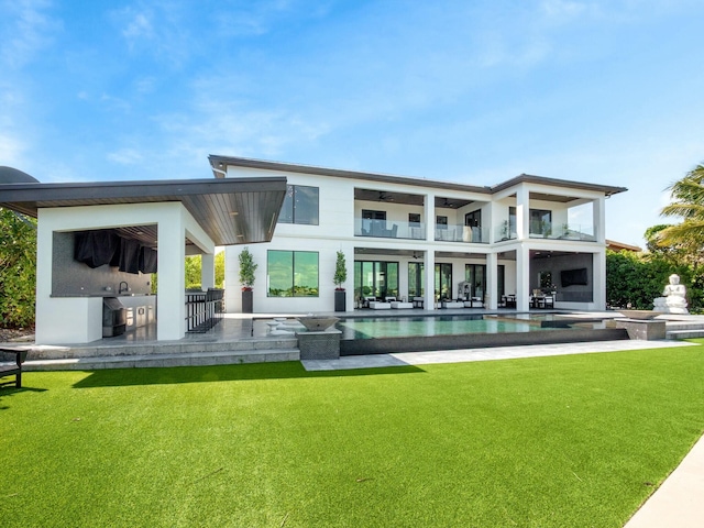 rear view of property with a balcony, an outdoor kitchen, a lawn, and a patio area