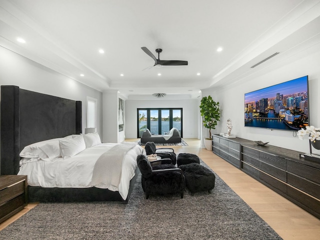 bedroom with a raised ceiling, light wood-style flooring, recessed lighting, and visible vents