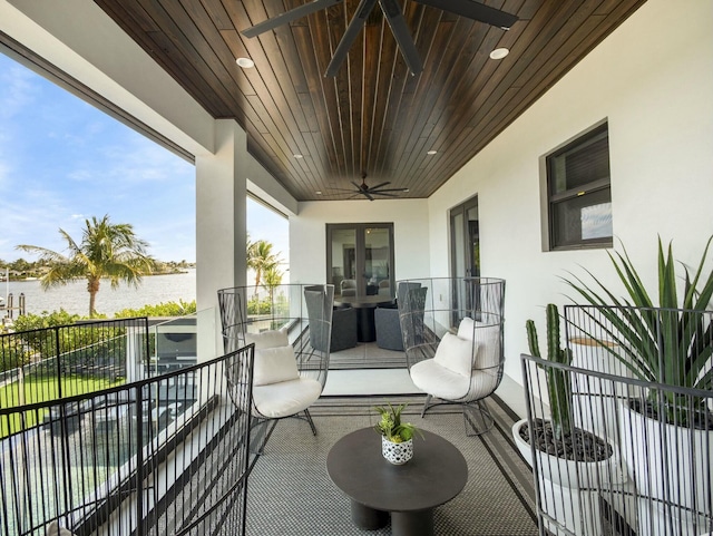 balcony with outdoor dining area, a ceiling fan, and a water view