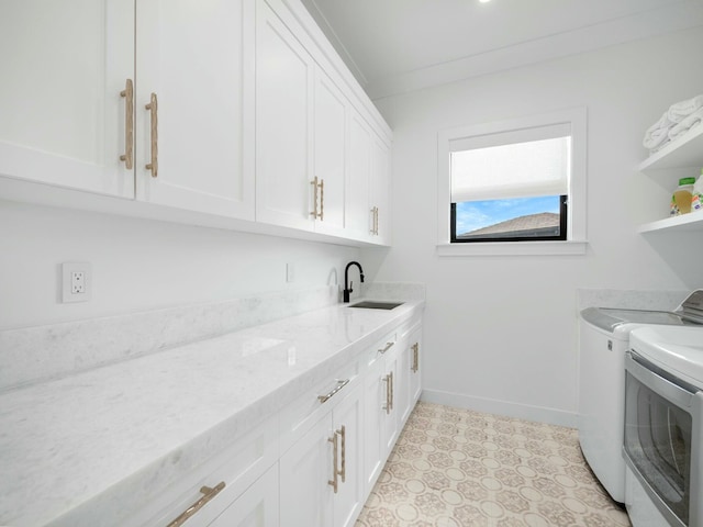 washroom featuring cabinet space, washing machine and dryer, baseboards, and a sink