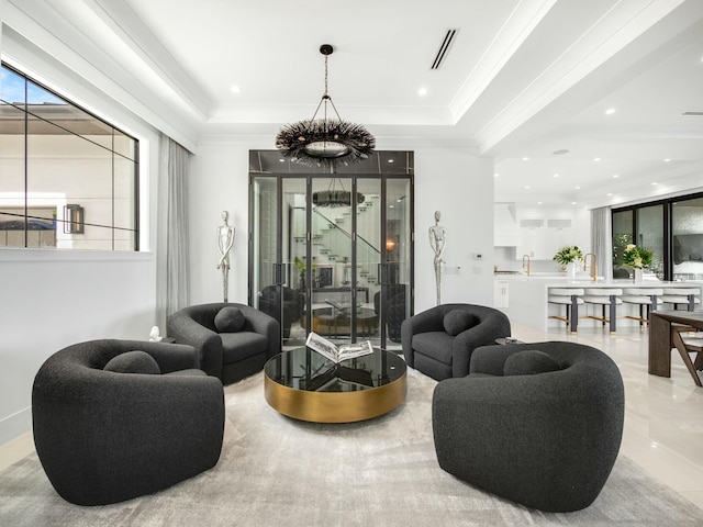 living area featuring a healthy amount of sunlight, a tray ceiling, and ornamental molding