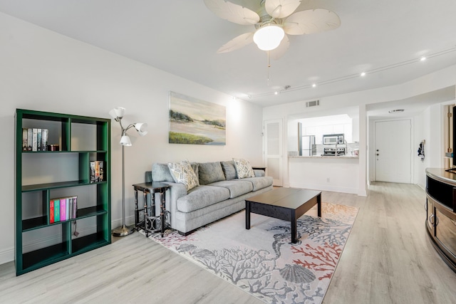 living area with baseboards, a ceiling fan, visible vents, and light wood-style floors