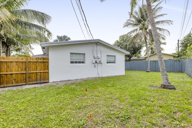 back of house featuring a fenced backyard, a lawn, and stucco siding