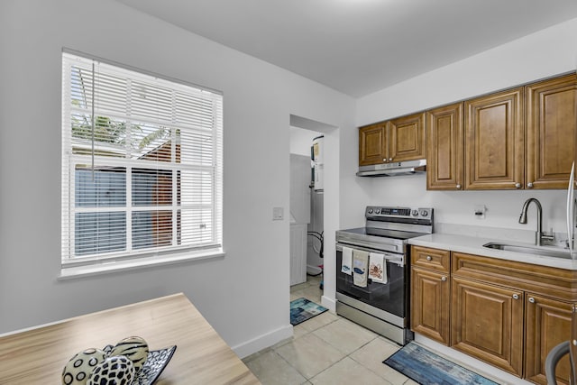 kitchen featuring light tile patterned floors, under cabinet range hood, a sink, light countertops, and stainless steel electric range