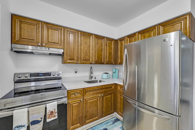 kitchen featuring light countertops, appliances with stainless steel finishes, brown cabinetry, a sink, and under cabinet range hood