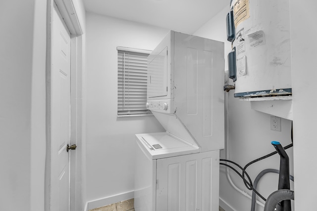 clothes washing area with stacked washer / drying machine, laundry area, and baseboards