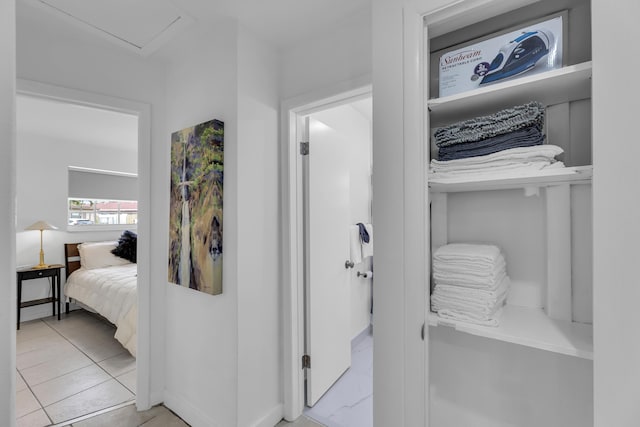 bedroom featuring light tile patterned floors and attic access