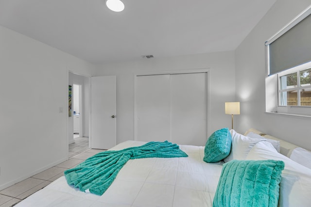 bedroom featuring light tile patterned floors, visible vents, and a closet