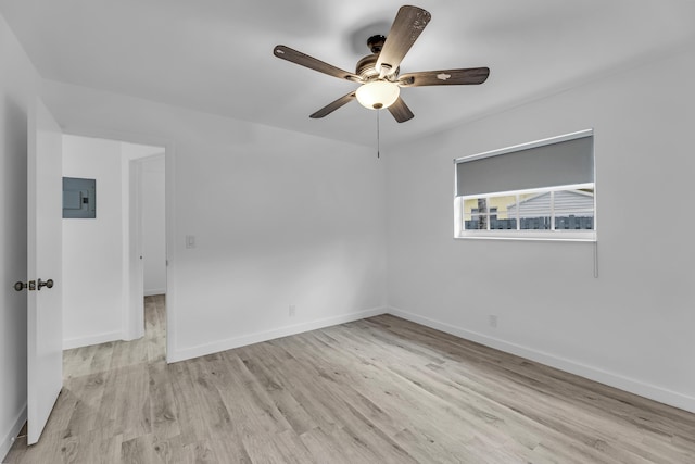 unfurnished room with light wood-style floors, ceiling fan, electric panel, and baseboards