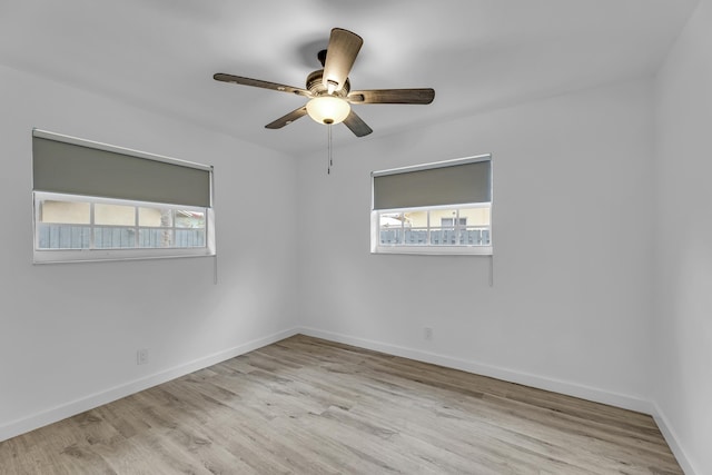 empty room with ceiling fan, light wood-style flooring, and baseboards