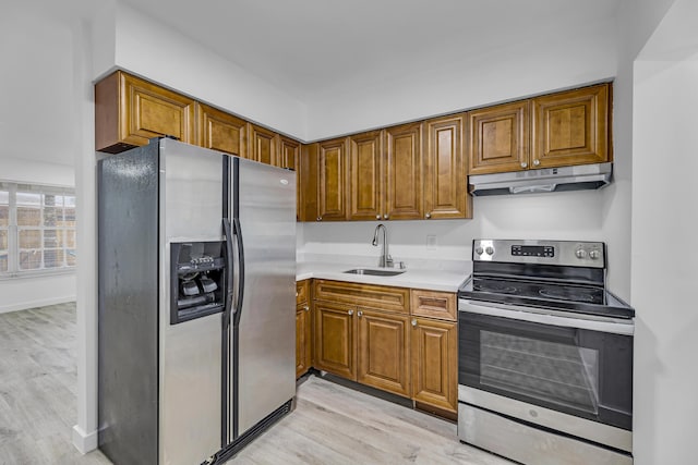 kitchen featuring light countertops, appliances with stainless steel finishes, brown cabinetry, a sink, and under cabinet range hood