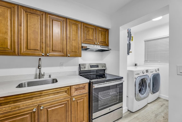 kitchen featuring brown cabinetry, stainless steel electric range oven, under cabinet range hood, washing machine and dryer, and a sink