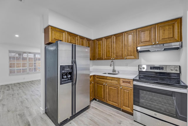 kitchen featuring under cabinet range hood, a sink, light countertops, appliances with stainless steel finishes, and brown cabinetry