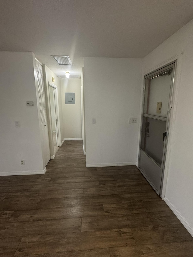 hallway with dark wood-style floors, visible vents, attic access, and baseboards