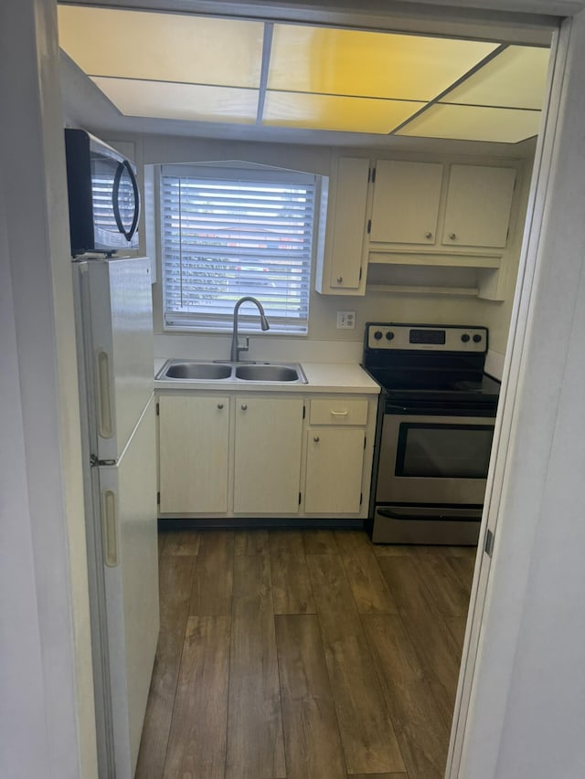 kitchen featuring appliances with stainless steel finishes, light countertops, a sink, and dark wood-style floors