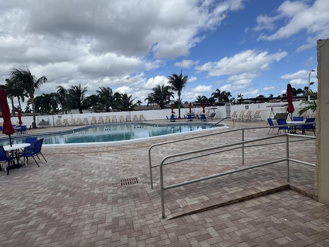 community pool with fence and a patio