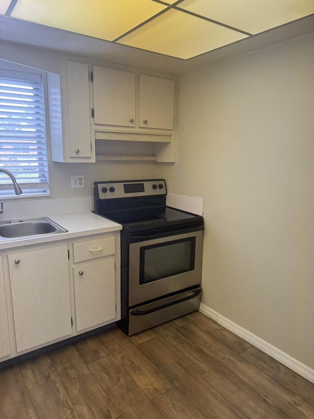 kitchen with electric range, baseboards, dark wood-type flooring, light countertops, and a sink