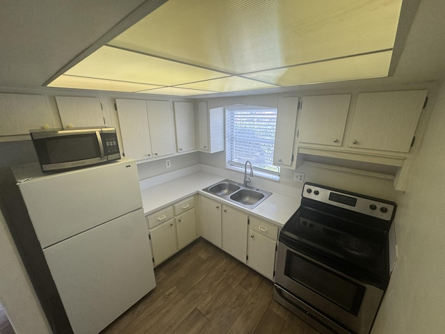 kitchen featuring stainless steel appliances, light countertops, dark wood-type flooring, white cabinets, and a sink