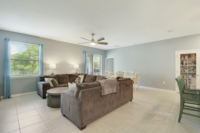 living room featuring light tile patterned floors, ceiling fan, visible vents, and baseboards