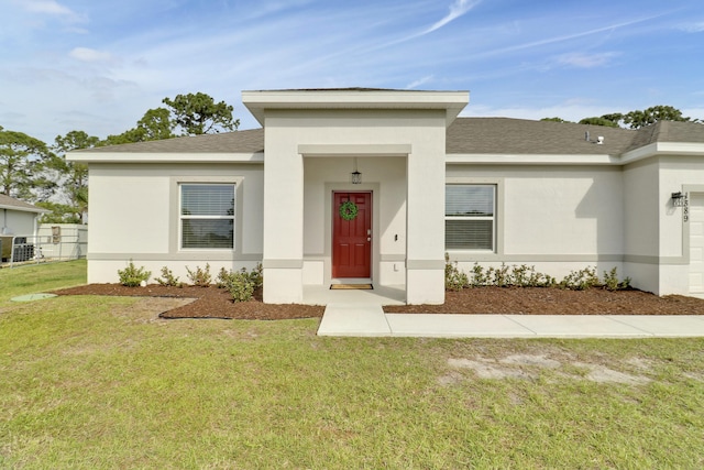 view of front of home featuring a garage, central air condition unit, a front lawn, and stucco siding