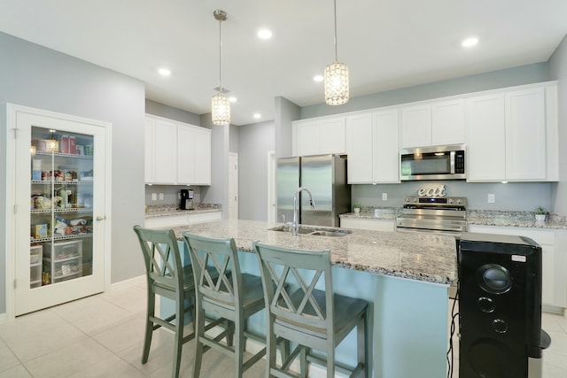 kitchen featuring white cabinets, a sink, stainless steel appliances, and a center island with sink