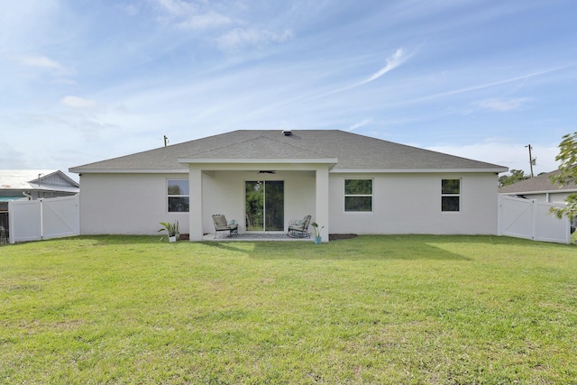 rear view of house featuring ceiling fan, a gate, and a yard