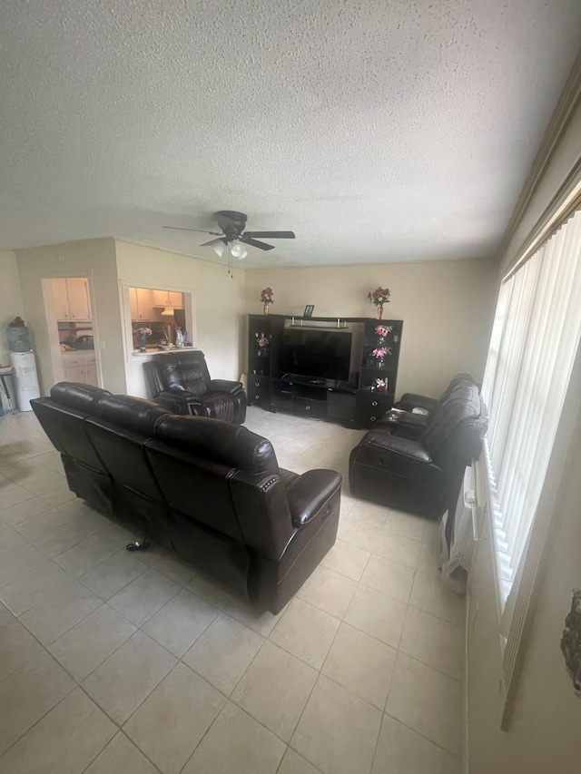 living area with a ceiling fan, light tile patterned flooring, and a textured ceiling