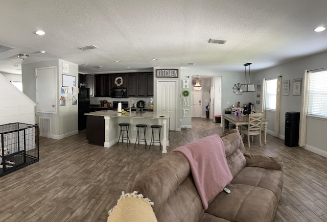 6101 NW Painted Bunting Ct, Port Saint Lucie, FL 34986 - living room featuring a textured ceiling, wood finished floors, baseboards, and recessed lighting