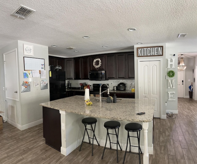 6101 NW Painted Bunting Ct, Port Saint Lucie, FL 34986 - kitchen with stainless steel microwave, wood finished floors, a kitchen breakfast bar, baseboards, and a textured ceiling