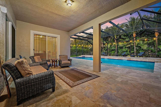 pool at dusk featuring an outdoor pool, glass enclosure, and a patio