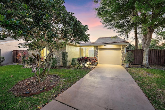 view of front of home featuring stucco siding, a front yard, fence, a garage, and driveway