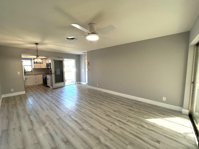 unfurnished living room with baseboards, light wood-style flooring, visible vents, and a ceiling fan