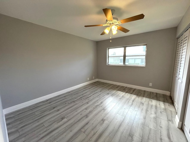 unfurnished bedroom with a ceiling fan, a closet, light wood finished floors, and baseboards